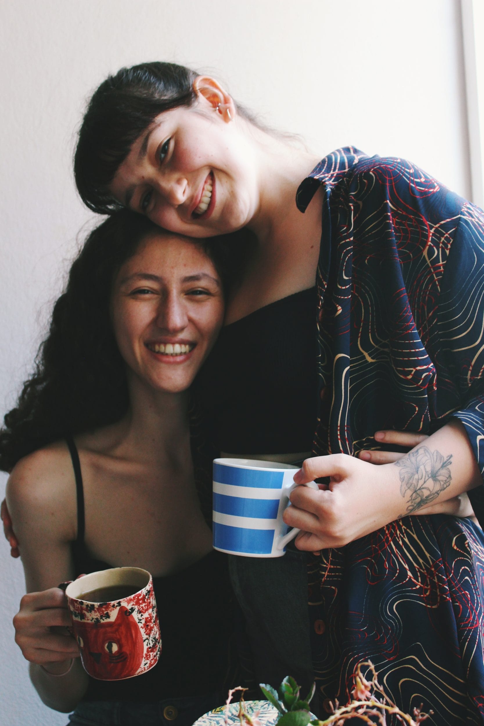 non-traditional relationship couple with two women drinking coffee and smiling for the camera.