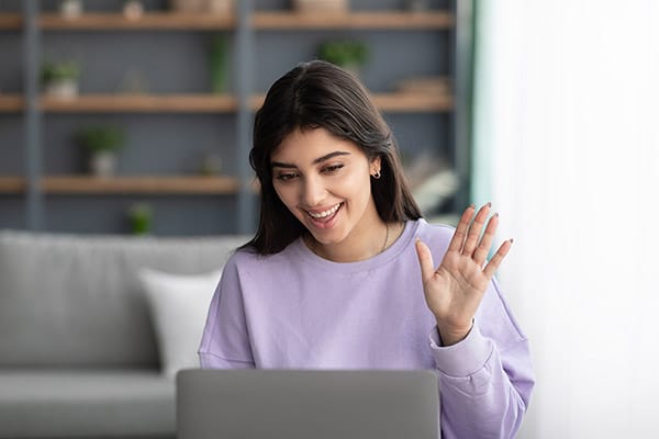 Happy young woman using laptop for virtual therapy, having video call at home.
